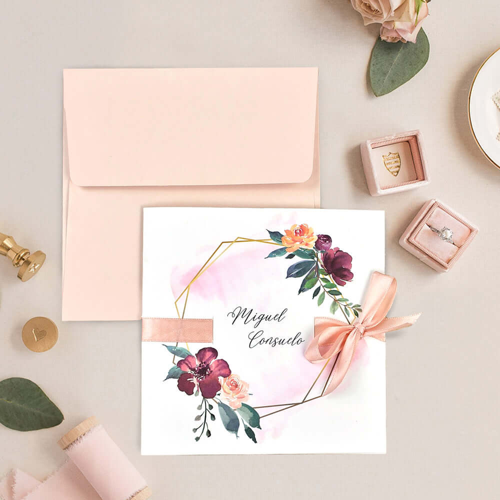 Elegant floral wedding invitation with a peach envelope, featuring vibrant watercolor blooms and a satin ribbon.