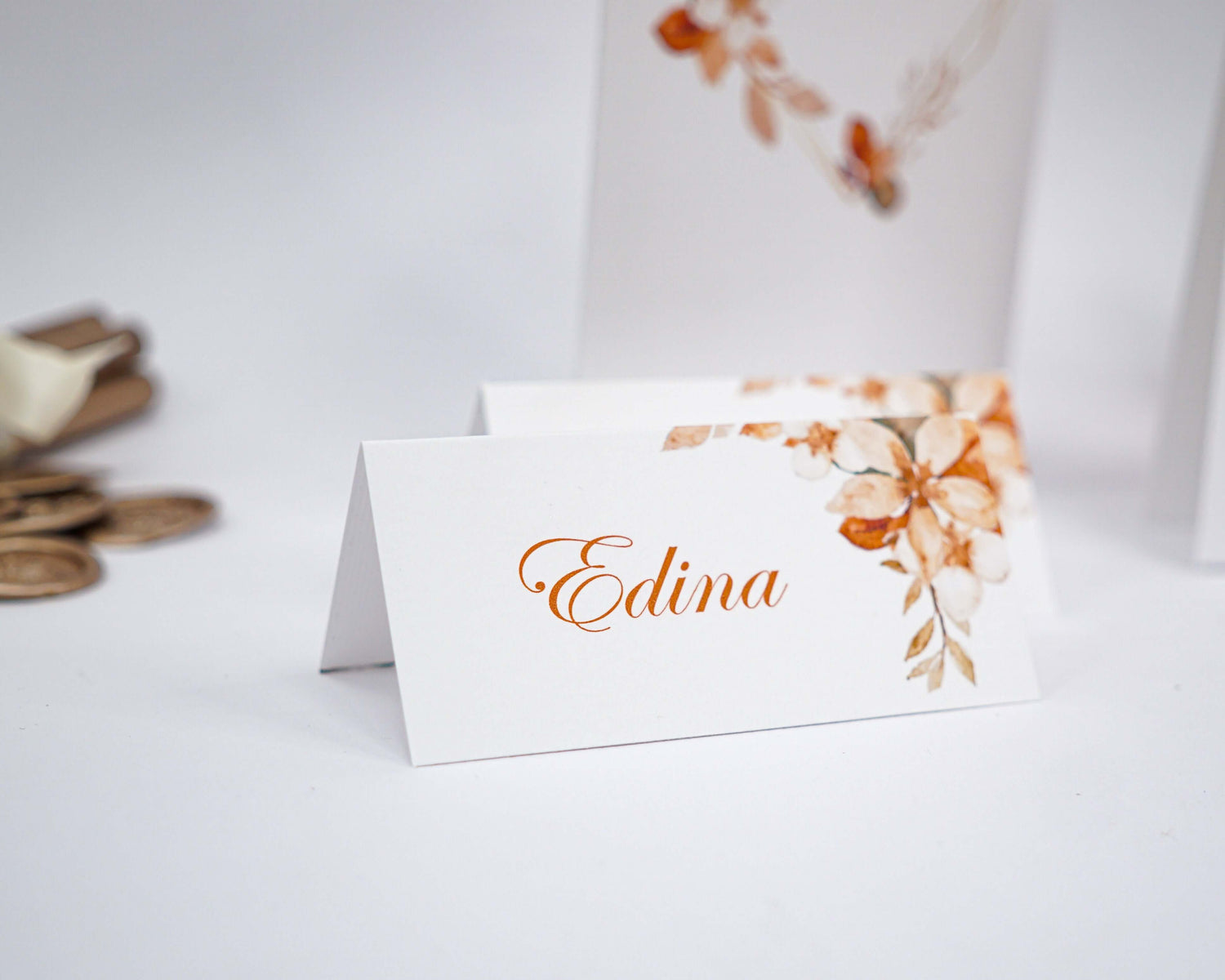 Elegant place card with floral design, featuring the name Edina in stylish orange script.